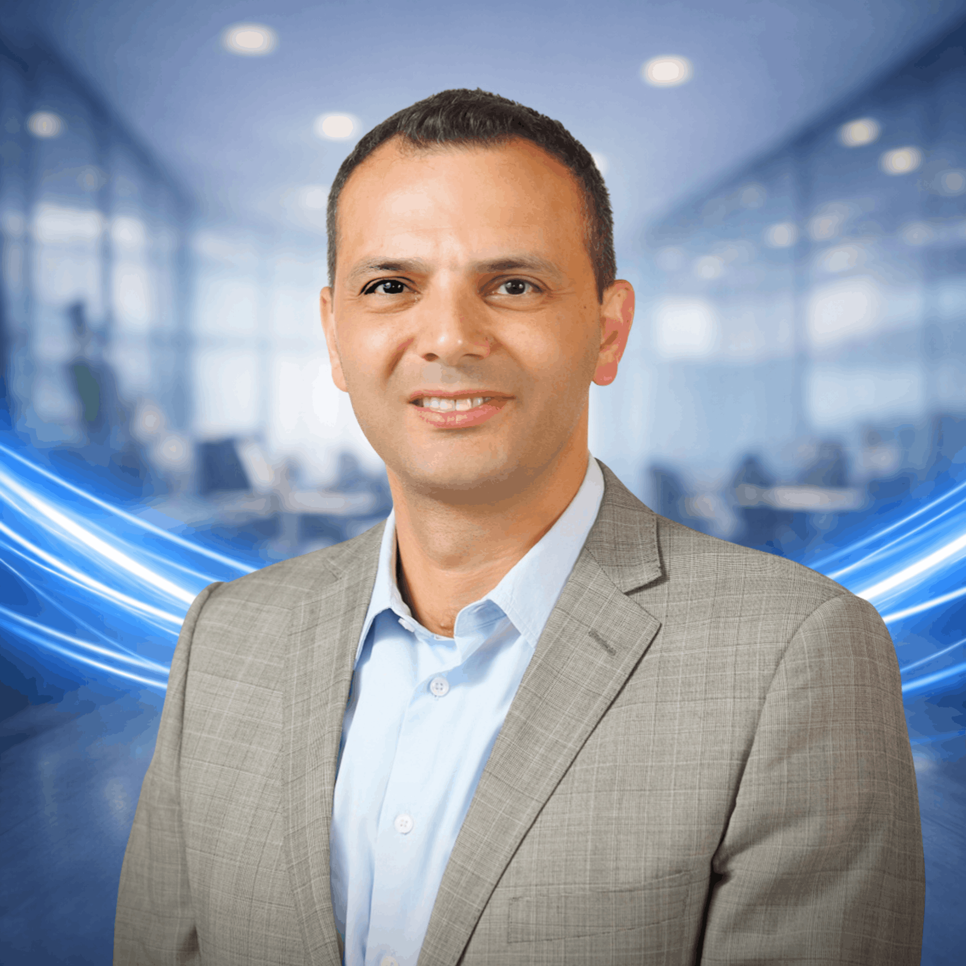 Antonio Khalil in a light gray suit and blue shirt, posing confidently with blue light streaks in an office background.